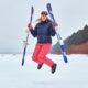 cheerful woman wearing warming sportswear holding skis jumping snowy beach 80x80