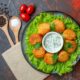 top view cheese balls plate with lettuce sauce cherry tomatoes wooden spoons black peppers dark surface 80x80